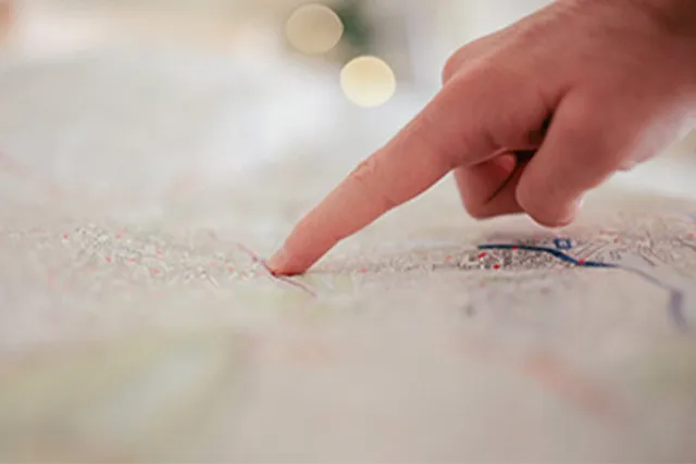 A finger pointing to a spot on a map