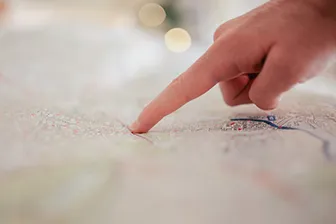 A finger pointing to a spot on a map